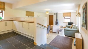 A modern kitchen with white cabinets, a black tiled floor, and a dining area with a sofa and table. - 1 Bed in Lochgilphead (oc-ca304) (Lochgilphead)