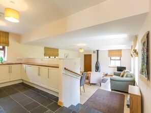 A modern kitchen with white cabinets, a black tiled floor, and a dining area with a sofa and table. - 1 Bed in Lochgilphead (oc-ca304) (Lochgilphead)