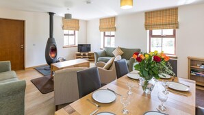 A modern living room with a fireplace, a dining area with a table set for two, and a sofa. - 1 Bed in Lochgilphead (oc-ca304) (Lochgilphead)