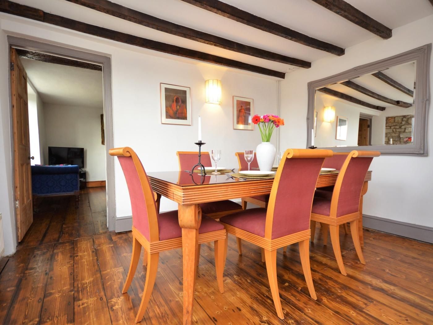 A dining area with a wooden table, red upholstered chairs, and a vase with flowers.