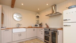 A kitchen with white cabinets, a built-in oven, a microwave, and a stainless steel range hood. - 2 Bed in West Linton (oc-76383) (West Linton)