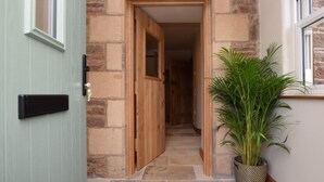 A stone building entrance with a wooden door labeled 'Failette,' a potted plant, and a tiled floor. - 2 Bed in West Linton (oc-76383) (West Linton)