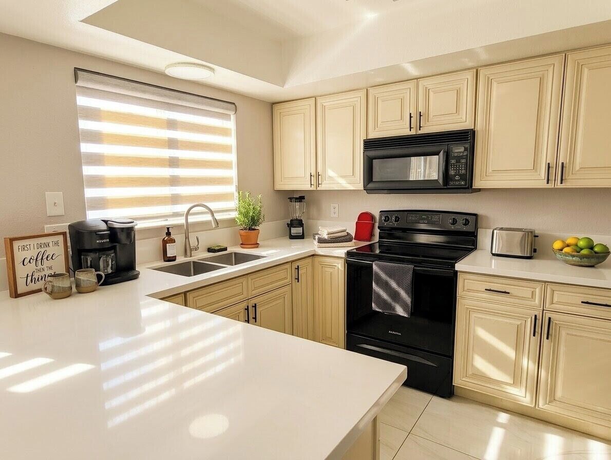 A kitchen with a coffee maker, microwave, toaster, and a bowl of fruit on the counter.