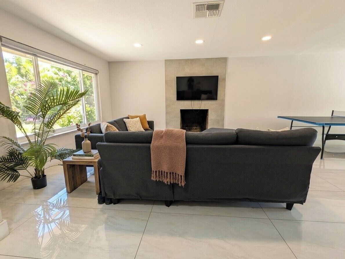 A modern living room with a sofa, a coffee table, a fireplace, and a television mounted on the wall.