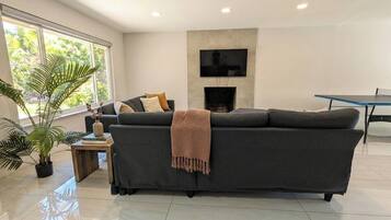 A modern living room with a sofa, a coffee table, a fireplace, and a television mounted on the wall.