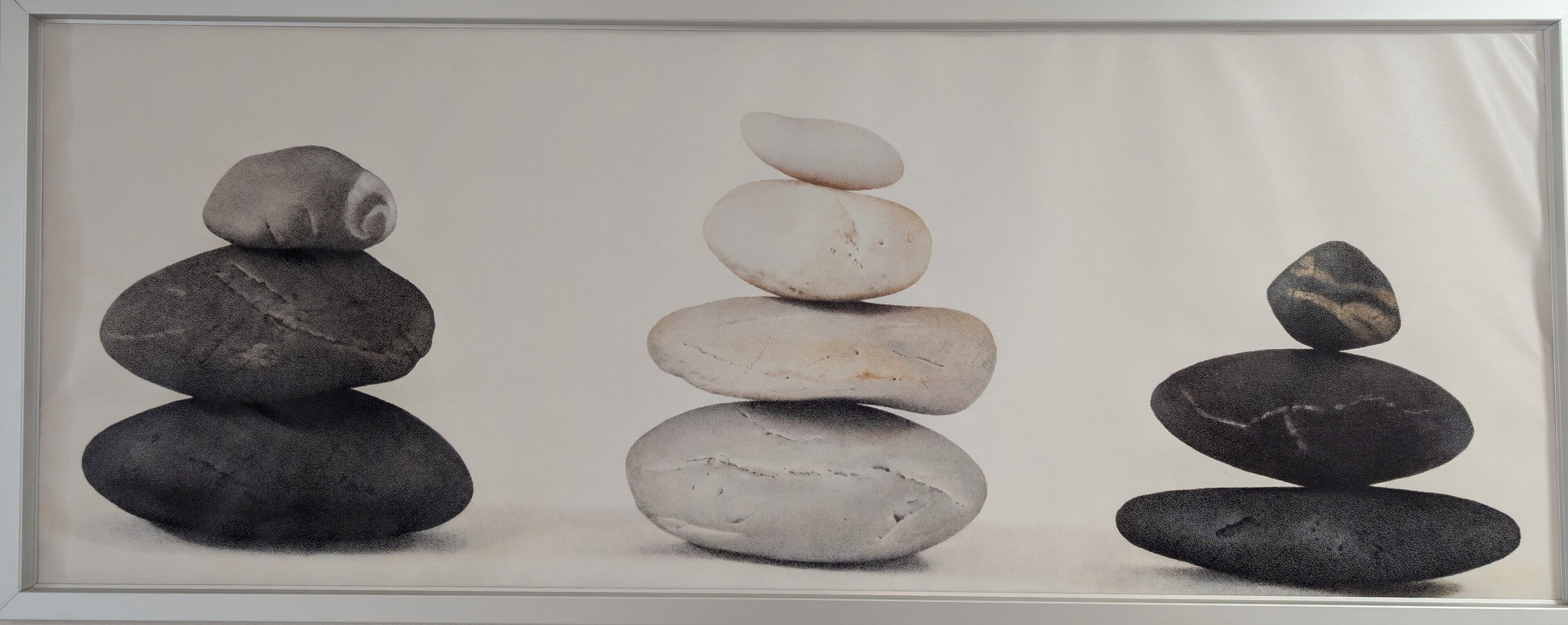 A framed photograph of three stacks of stones.