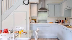 A modern kitchen with white cabinets, a stainless steel range hood, and a dining area with a glass table and chairs. - 1 Bed in Harrogate (oc-76511) (Summerbridge)