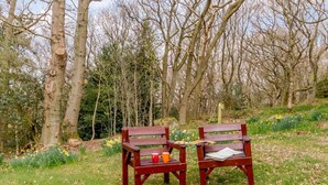 Two wooden benches in a grassy area with trees and daffodils in the background. - 1 Bed in Harrogate (oc-76511) (Summerbridge)