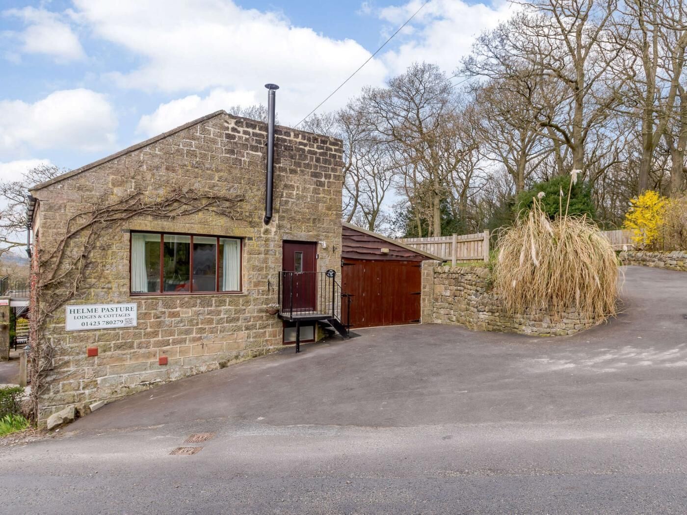 A stone building with a sign for 'Helme Pasture Lodges & Cottages.'