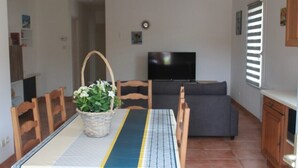 A dining area with a table, chairs, a TV, and a sofa. - Le Petit Balou Vacation Rental, Dordogne. A comfortable home near Bergerac (Lamonzie-Saint-Martin)