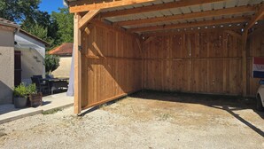A wooden structure with a covered area, a gravel ground, and a small table with chairs. - Le Petit Balou Vacation Rental, Dordogne. A comfortable home near Bergerac (Lamonzie-Saint-Martin)