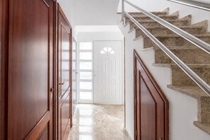 A hallway leading to a staircase with a handrail, wooden doors, and a door with a window. - GuestReady - La Suerte Family Spacious (Las Palmas de Gran Canaria)