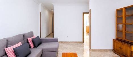 Uma sala de estar com sofá cinza, mesa de centro de madeira e um armário de madeira.