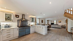 A spacious kitchen with modern appliances, a dining area, and a living room with a sofa and TV. - 3 Bed in Arthog (oc-77304) (Arthog)