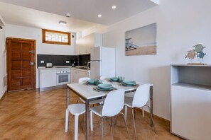 A compact kitchen with a dining area, a wooden door, and a small refrigerator. - GuestReady - Tenesor Sun Beach Resort (Las Palmas de Gran Canaria)