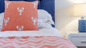 Ein Bett mit einem gemusterten Kopfkissen, einer gestreiften Decke und einem Nachttisch mit einer Lampe und einer Wasserflasche.