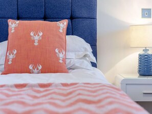 A bed with a patterned pillow, a striped blanket, and a nightstand with a lamp and a water bottle. - 2 Bed in Bideford (oc-77289) (Northam)