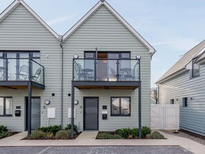 A two-story residential building with a balcony on the upper floor, a front door, and a small garden area. - 2 Bed in Bideford (oc-77289) (Northam)
