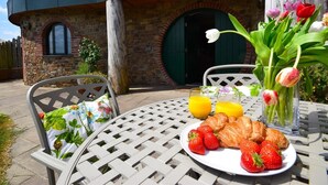 An outdoor dining area with a table set for breakfast, including croissants, strawberries, and juice. - 2 Bed in Bideford (oc-77292) (Bideford)
