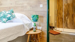 A hotel room with a bed, a small table with a bottle, a lamp, and a shower area. - 2 Bed in Bideford (oc-77292) (Bideford)