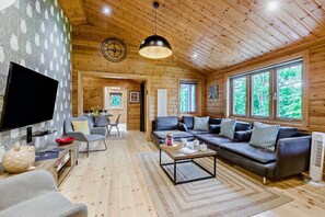 A spacious living area with a flat-screen TV, a sofa set, and a dining table.