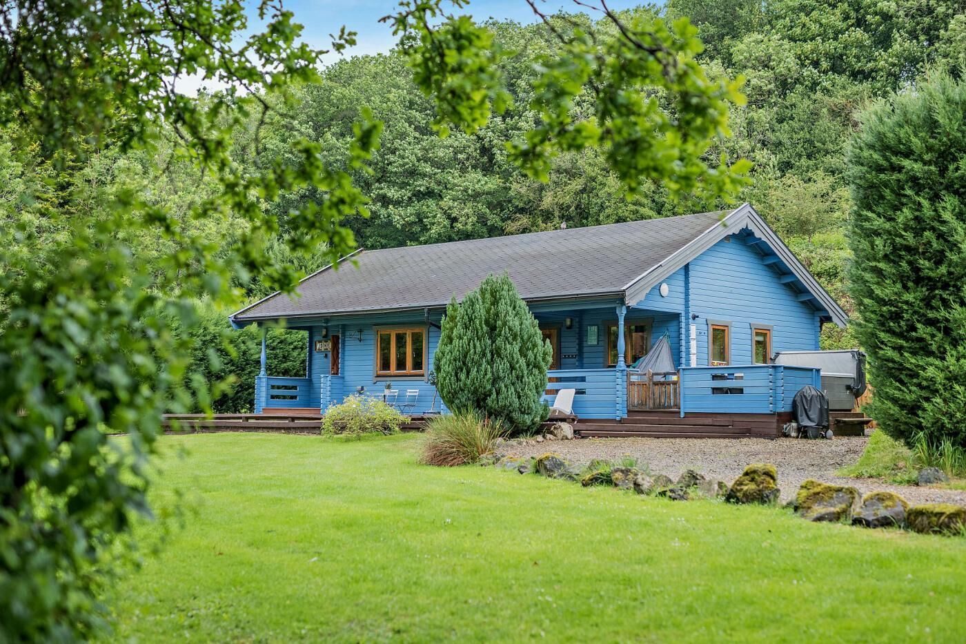 Ein blaues Haus mit Veranda, umgeben von viel Grün.