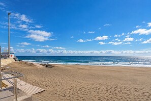 A beach with a lifeguard tower, clear skies, and calm ocean waves. - GuestReady - San Agustin Blue Flag Beach (San Agustin)