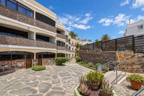 A multi-story building with a stone facade, a covered walkway, and potted plants. - GuestReady - San Agustin Blue Flag Beach (San Agustin)