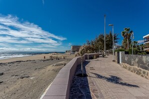 Um caminho costeiro com trilho de pedra, praia e vista para o oceano.