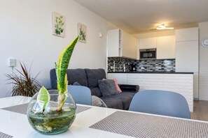 A modern living room with a dining table, a sofa, and a kitchen in the background. - GuestReady - San Agustin Blue Flag Beach (San Agustin)