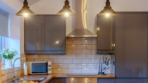 Una cucina moderna con elettrodomestici in acciaio inossidabile, un piano di lavoro in legno e luci a sospensione.