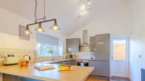Una cucina moderna con isola centrale, sgabelli da bar, frigorifero e una finestra che offre luce naturale.