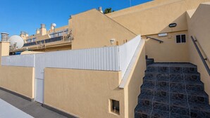 Um edifício residencial com fachada bege, cerca branca e um conjunto de degraus de pedra que levam a uma porta.