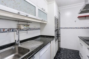 Una cocina compacta con un lavamanos de acero inoxidable, lavavajillas y horno integrado.