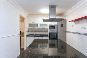 Eine kleine Küche mit Herd, Backofen, Mikrowelle und einer Edelstahl-Dunstabzugshaube.
