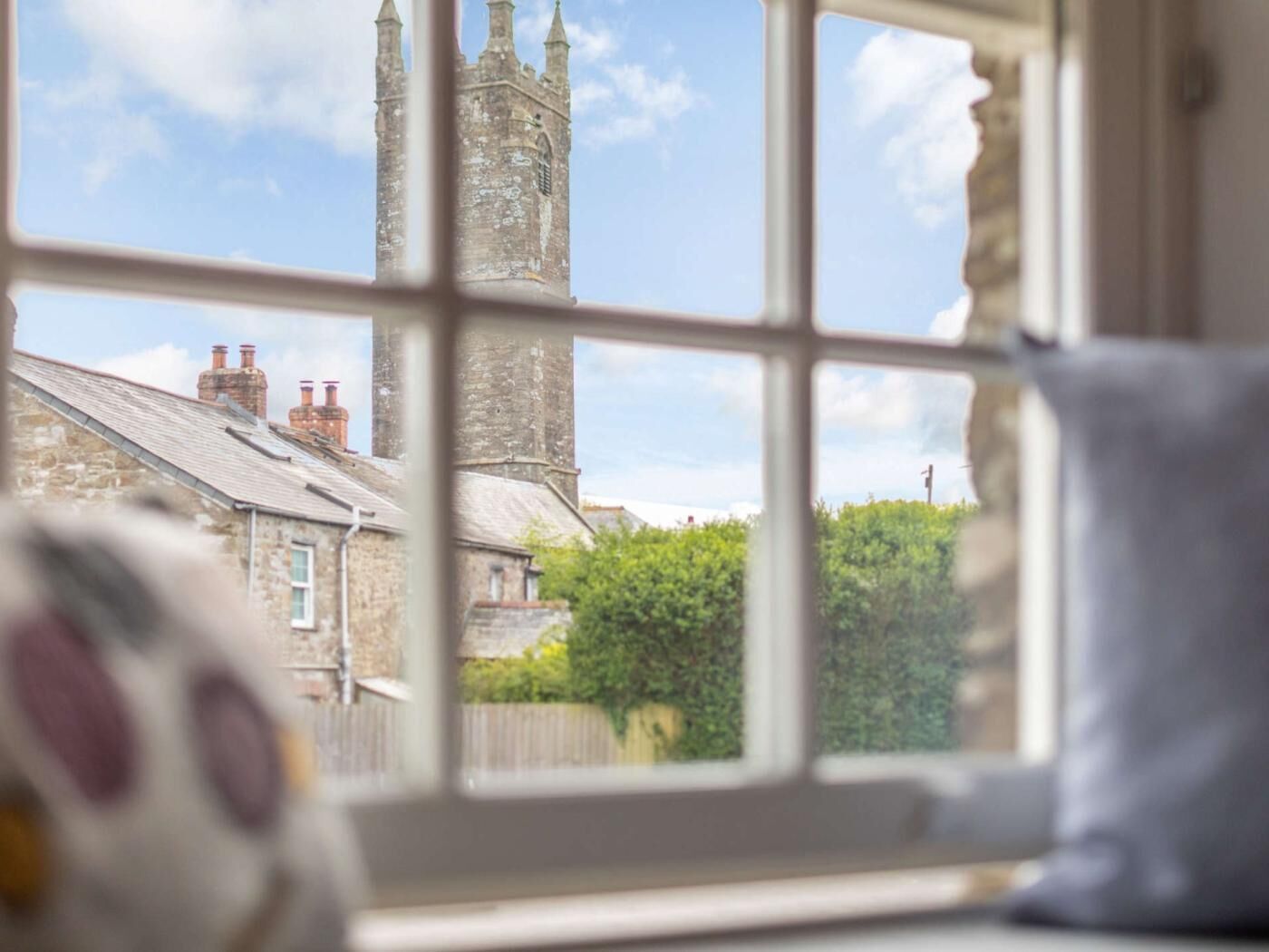 A window view of a stone building with a tower, likely a church or historical structure.