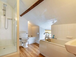 Ein Badezimmer mit Duschkabine aus Glas, Toilette, Badewanne und Holzboden.