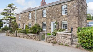 A stone building with multiple windows, a gated entrance, and surrounding greenery. - 2 Bed in Bodmin (oc-76604) (Saint Mabyn)