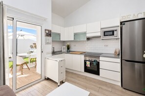 Eine moderne Küche mit weißen Schränken, einem Edelstahlkühlschrank, einer Mikrowelle und einem eingebauten Backofen.