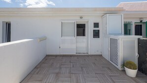 A rooftop terrace with a herringbone-patterned floor, a door with shutters, and a potted cactus. - GuestReady - Aguila Beachfront Apartment (San Agustin)