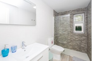 Uma casa de banho moderna com uma sanita, um lavatório branco e cabine de duche em vidro.