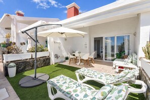 A patio with a dining table, chairs, and a cactus-themed sofa set. - GuestReady - Aguila Beachfront Apartment (San Agustin)