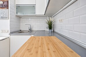A modern kitchen with white subway tiles, a wooden countertop, a stainless steel sink, and a potted plant. - GuestReady - Aguila Beachfront Apartment (San Agustin)