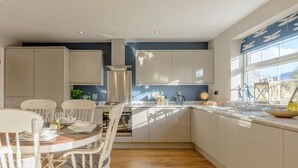Uma cozinha moderna com armários brancos, uma mesa de jantar com cadeiras e uma janela com vista.