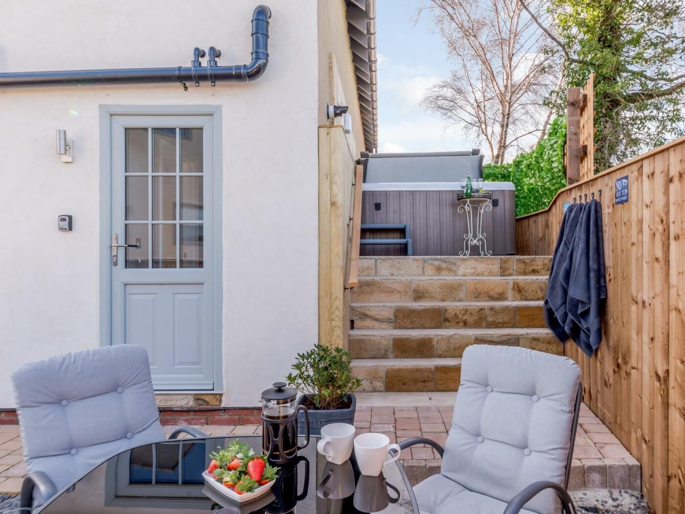 Une terrasse avec deux chaises, une cafetière et un saladier rempli de fraises.