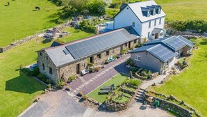 Ein Bauernhaus aus Stein mit Solaranlage, einer gepflasterten Auffahrt und einem gepflegten Rasen.
