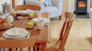 Ein gemütliches Frühstücksszenario mit Holztisch, Stühlen und einer Couch im Hintergrund.