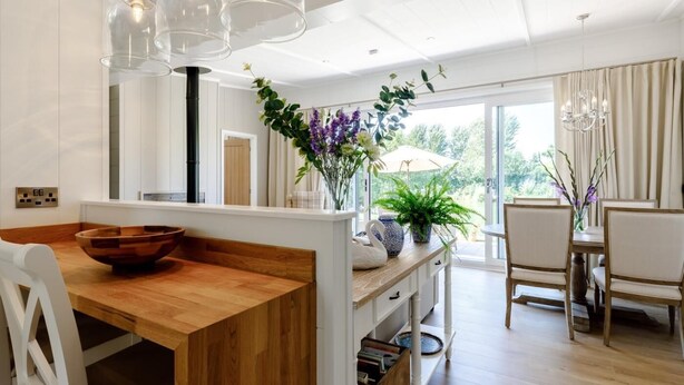 A modern kitchen with a wooden table, white chairs, and a dining area with a view. - 2 Bed in Ludlow (oc-78025) (Richards Castle)