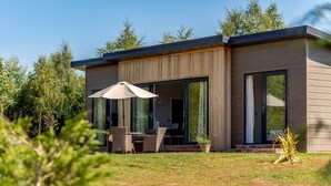 A modern house with a patio, outdoor furniture, and a large umbrella. - 2 Bed in Ludlow (oc-78025) (Richards Castle)