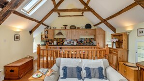 A loft-style room with exposed wooden beams, a kitchenette, a sofa, and a dining table. - 2 Bed in Bideford (oc-77915) (Appledore)